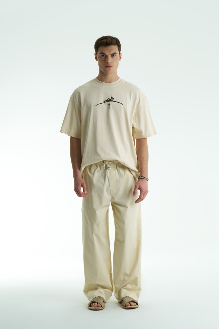 Cream Oversized cotton graphic T-shirt with minimalist chest logo and stitched back artwork patch, shown in multiple colorways on model