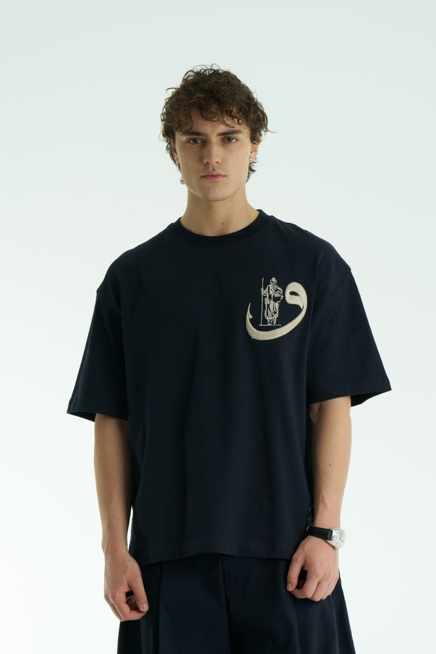 Navy Oversized cotton graphic T-shirt with small chest emblem and large ornate framed back print, shown in black, white, brown, and navy.