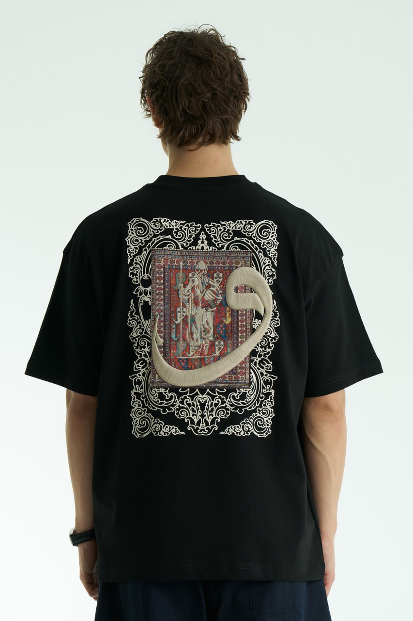 Black Oversized cotton graphic T-shirt with small chest emblem and large ornate framed back print, shown in black, white, brown, and navy.