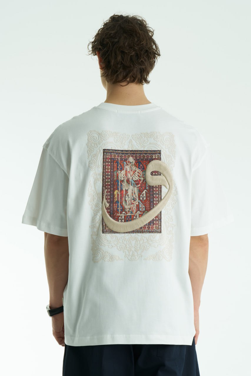 White Oversized cotton graphic T-shirt with small chest emblem and large ornate framed back print, shown in black, white, brown, and navy.