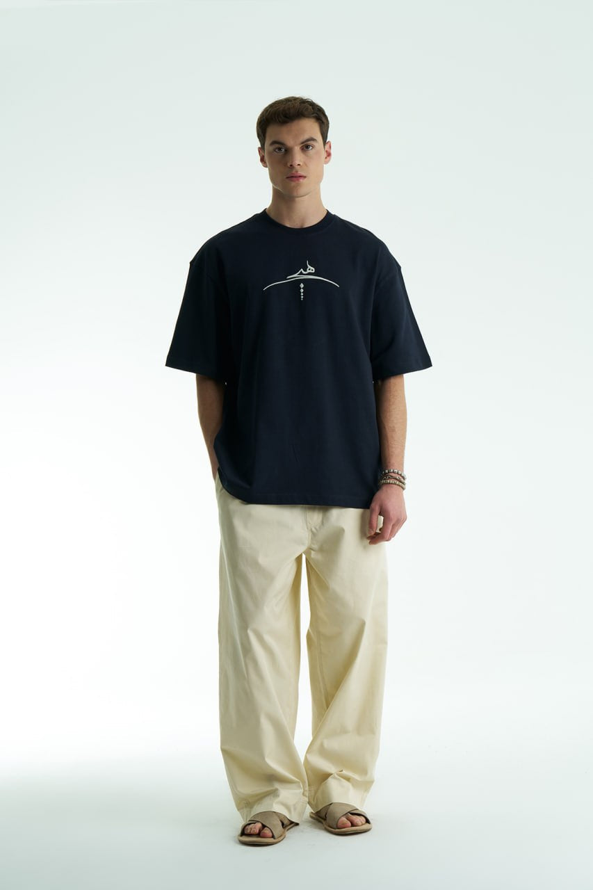 Navy Oversized cotton graphic T-shirt with minimalist chest logo and stitched back artwork patch, shown in multiple colorways on model