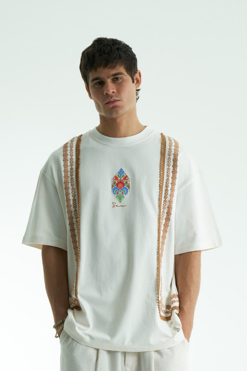 White Sam oversized crewneck graphic T-shirt with embroidered motif and ornate border trims in black, cream, and white colorways