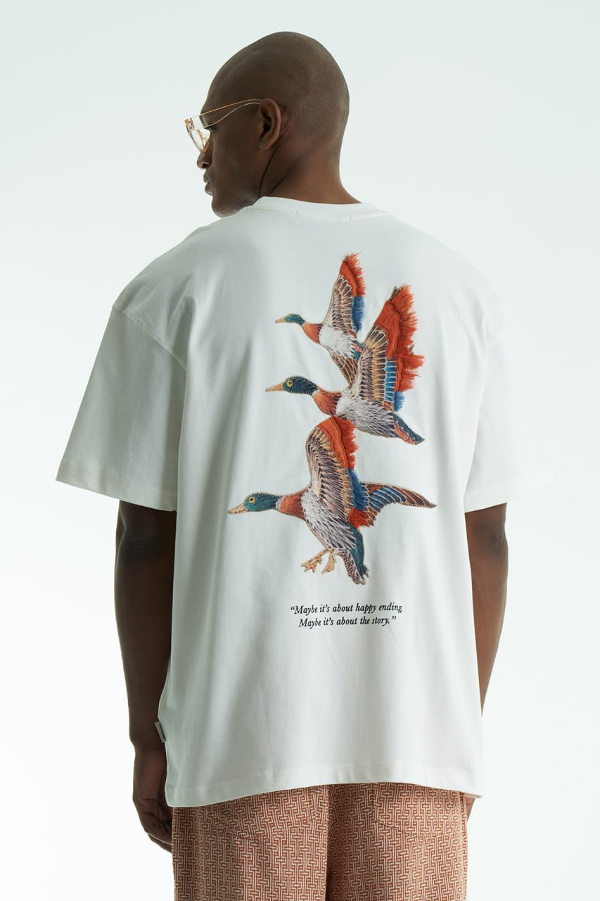 White Oversized cotton T-shirt with embroidered flying ducks and quote print, shown in multiple colorways front and back.