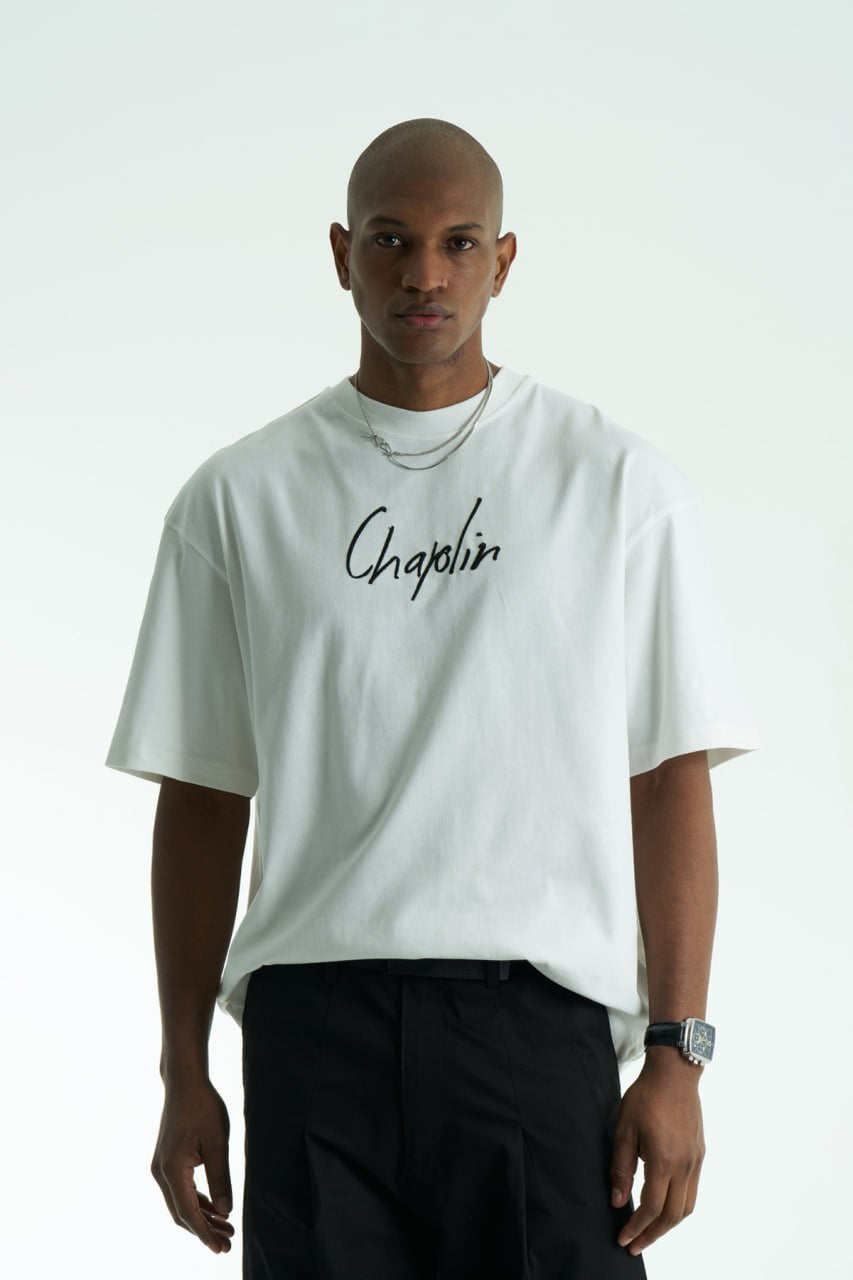 White Chaplin oversized cotton graphic T-shirt with front script logo and collage patch back, shown in black and white