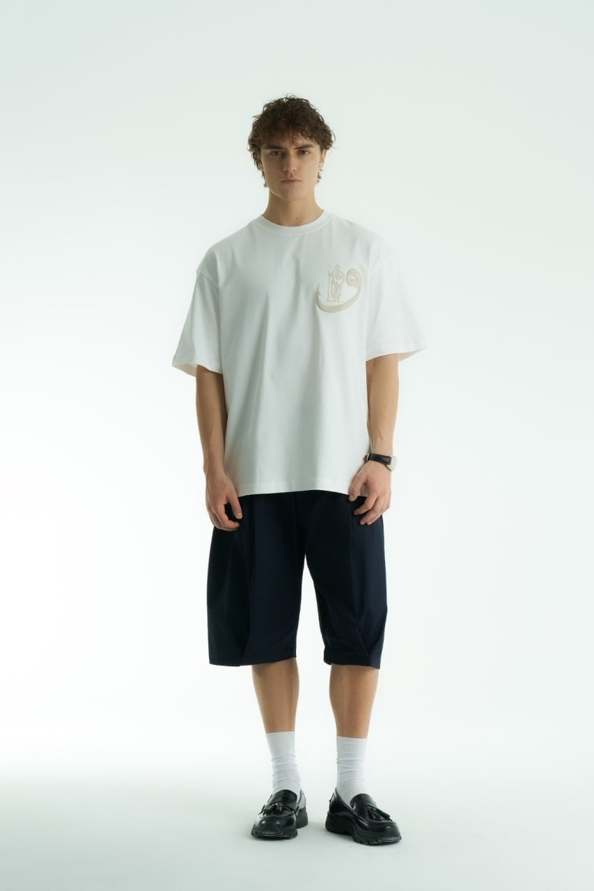 White Oversized cotton graphic T-shirt with small chest emblem and large ornate framed back print, shown in black, white, brown, and navy.