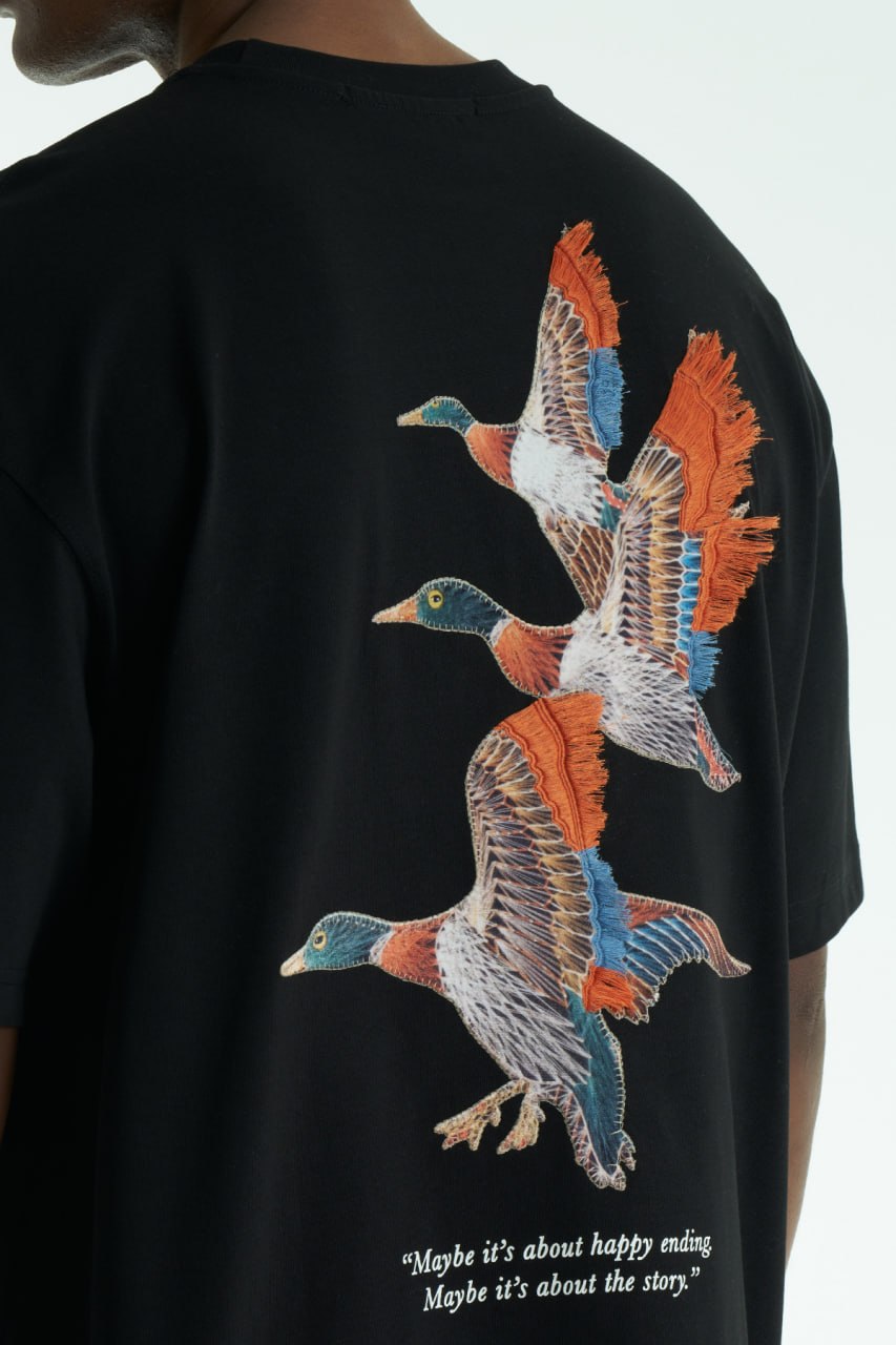 Black Oversized cotton T-shirt with embroidered flying ducks and quote print, shown in multiple colorways front and back.