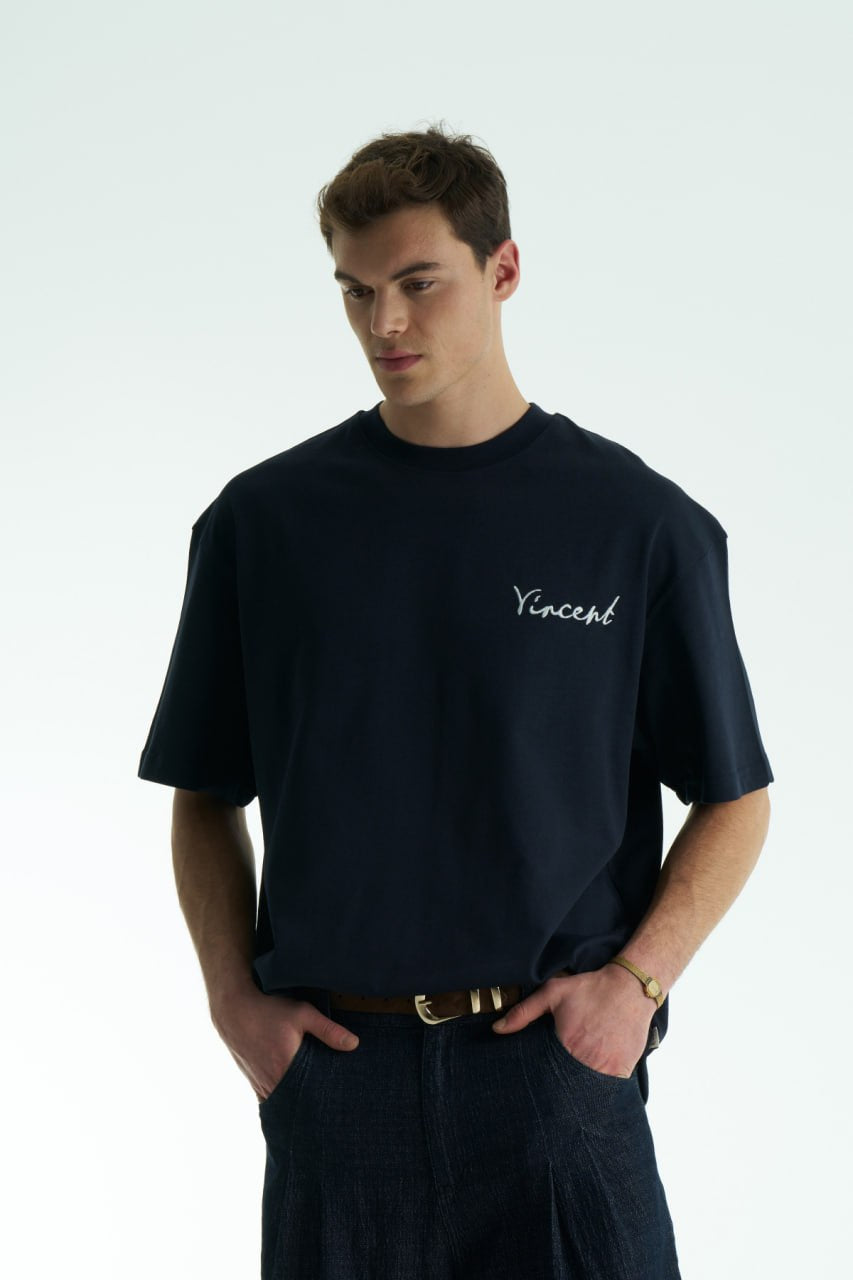 Black Vincent oversized crewneck graphic T-shirt with small chest logo and large illustrated back print, shown in black, white and cream.