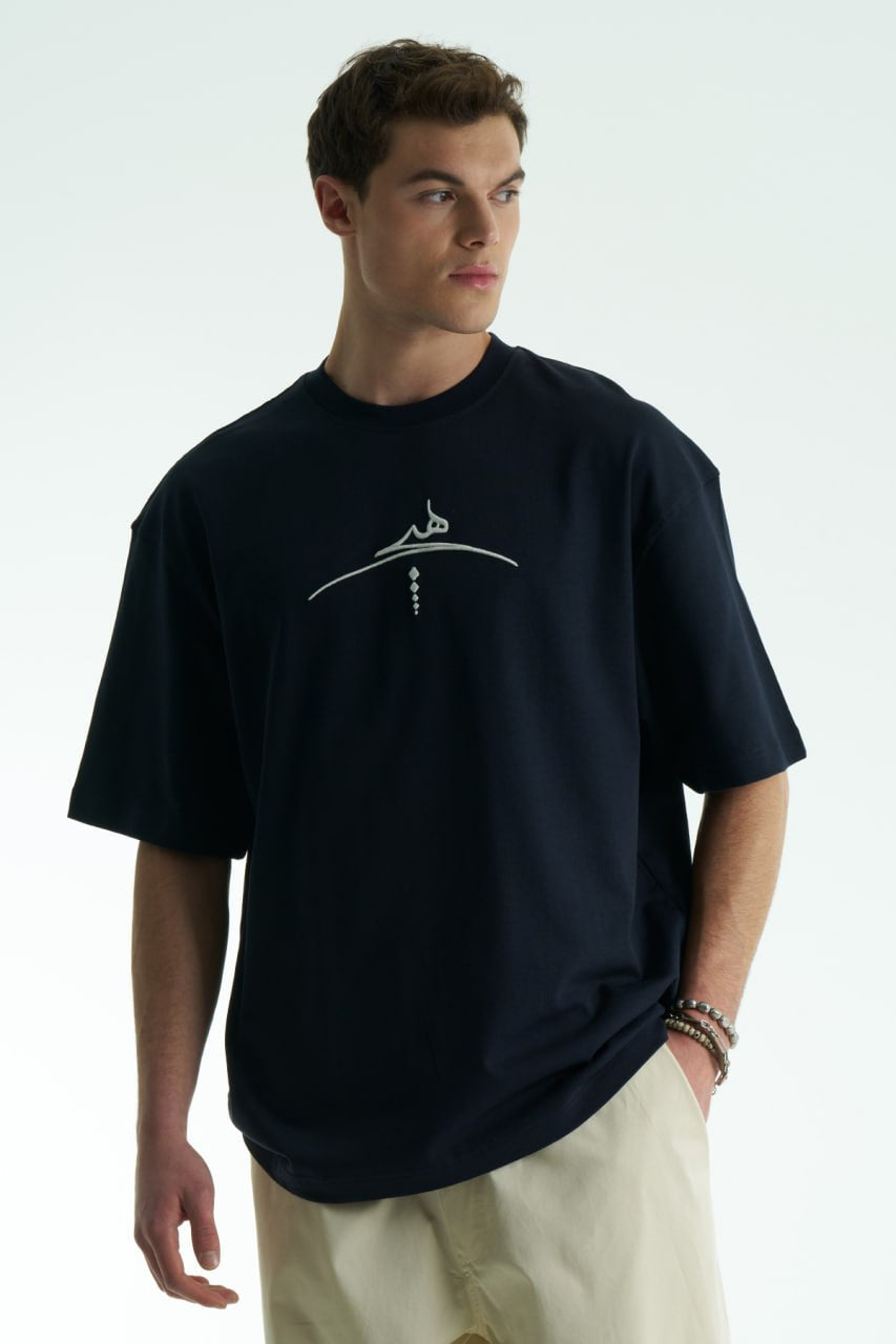 Navy Oversized cotton graphic T-shirt with minimalist chest logo and stitched back artwork patch, shown in multiple colorways on model