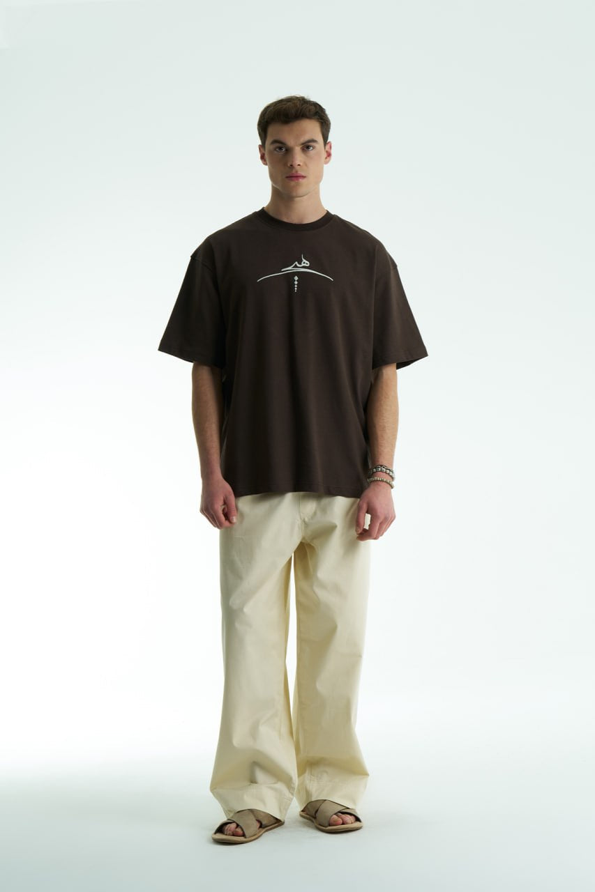 Dark Brown Oversized cotton graphic T-shirt with minimalist chest logo and stitched back artwork patch, shown in multiple colorways on model