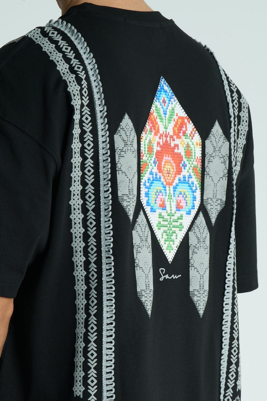 Black Sam oversized crewneck graphic T-shirt with embroidered motif and ornate border trims in black, cream, and white colorways