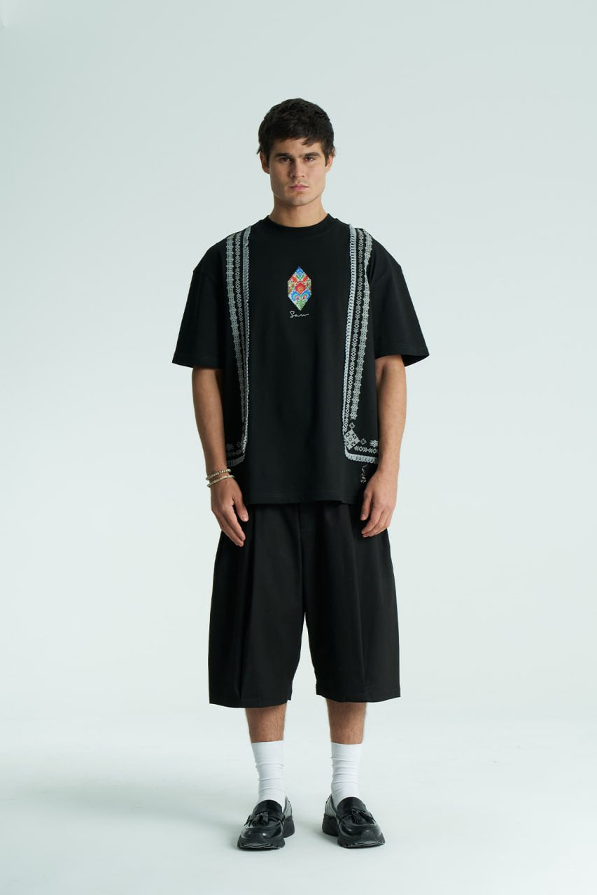 Black Sam oversized crewneck graphic T-shirt with embroidered motif and ornate border trims in black, cream, and white colorways