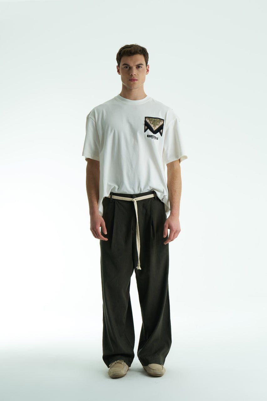White Oversized Memories Never Die cotton tee with chest pocket appliqué and scarf-style back yoke, shown in white, beige, and black.
