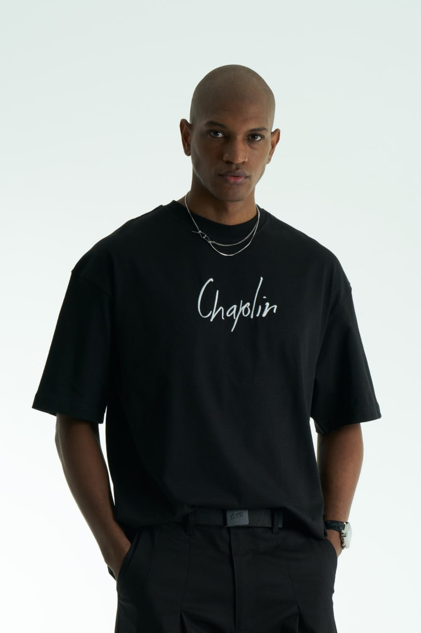 Black Chaplin oversized cotton graphic T-shirt with front script logo and collage patch back, shown in black and white