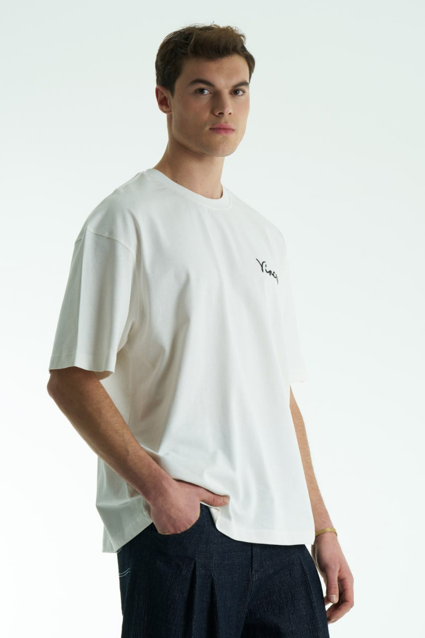 White Vincent oversized crewneck graphic T-shirt with small chest logo and large illustrated back print, shown in black, white and cream.